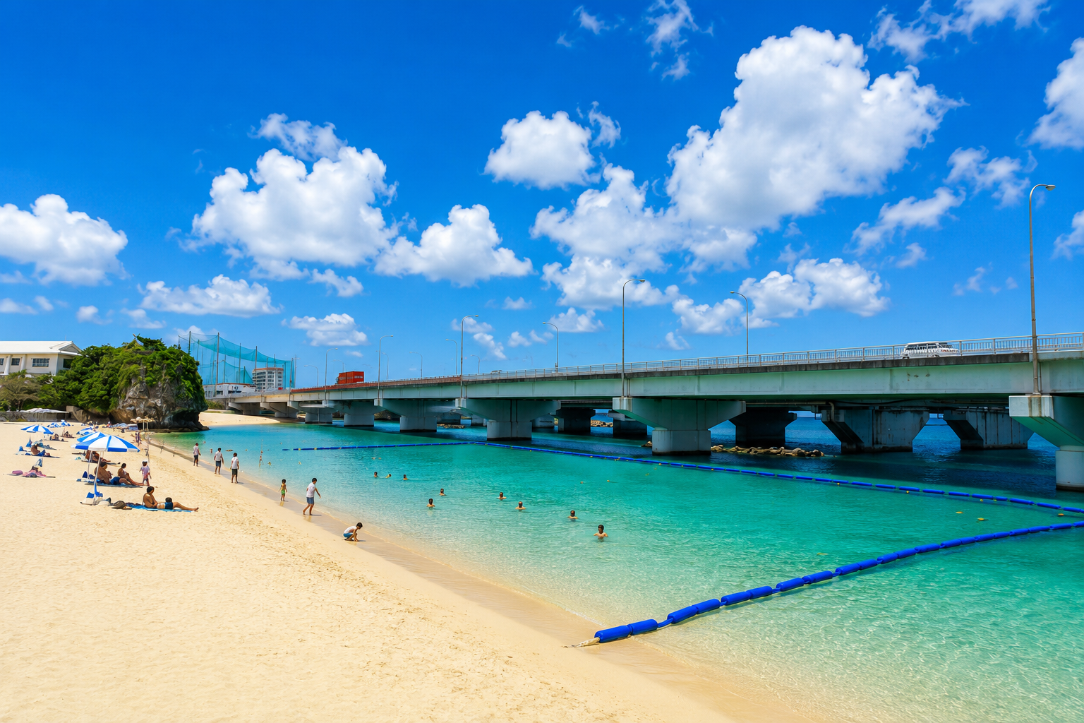 波の上ビーチの白い砂浜と透明なエメラルドグリーンの海。青空の下、海水浴を楽しむ人々やパラソルが並び、ビーチの上には大きな橋が架かっている沖縄の風景。