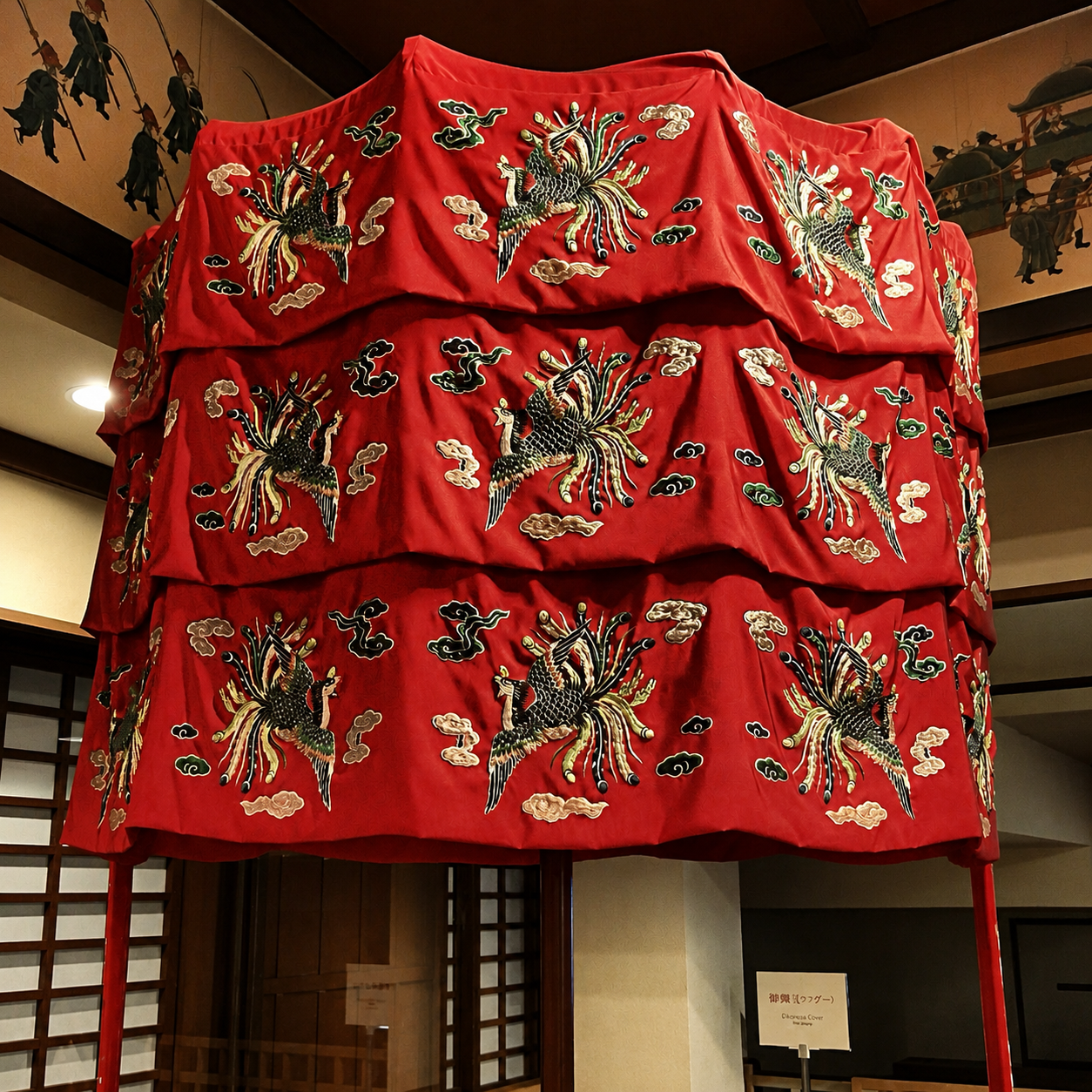 沖縄の伝統的な赤い祭礼用の覆いに、鳳凰や雲の美しい刺繍が施された様子