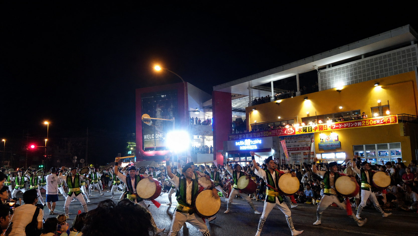 沖縄市の道ジュネーで、太鼓を叩きながら踊る演者たちと沿道を埋め尽くす観客の様子